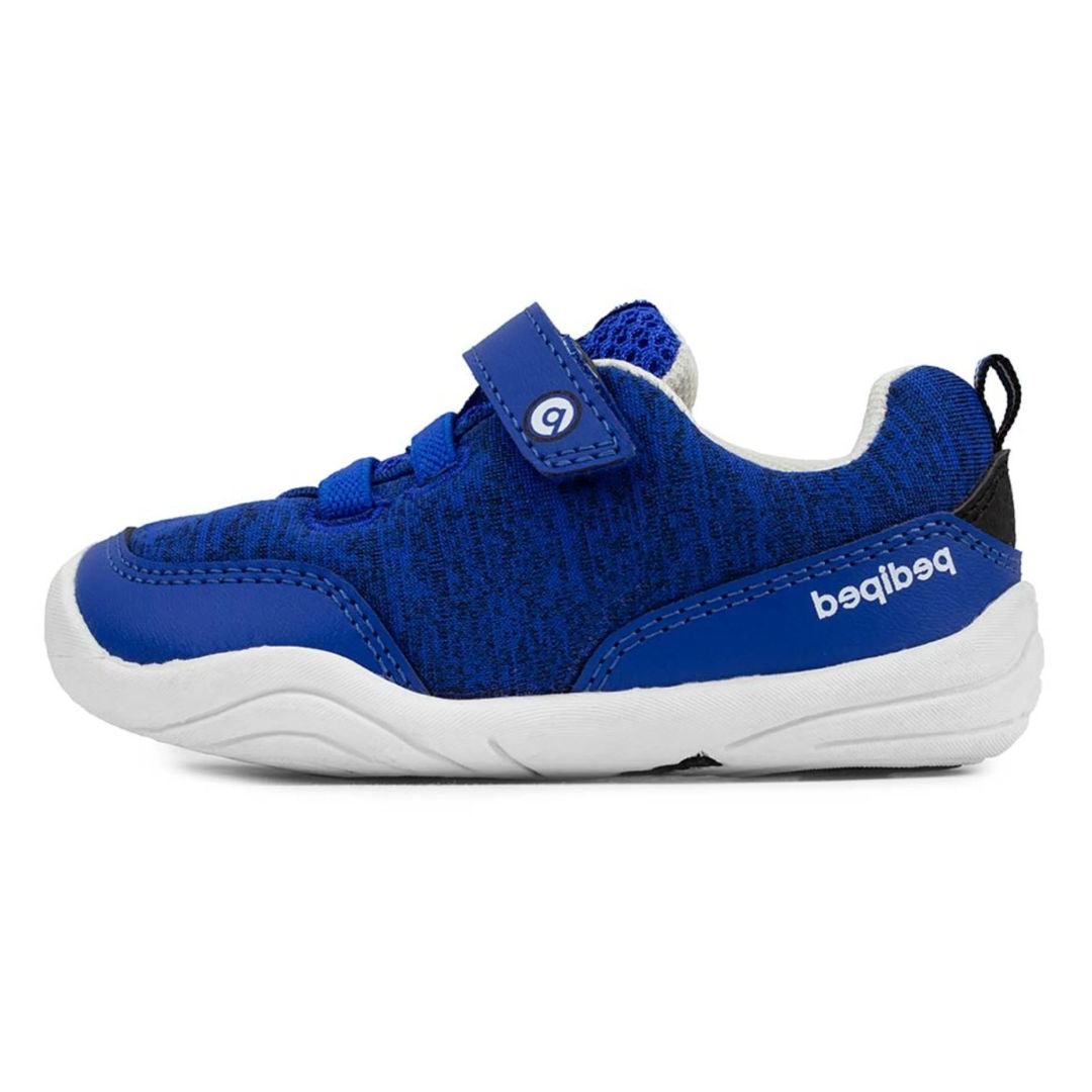 Basket bébé bleu avec velcro, lacets élastiques et semelle blanche.