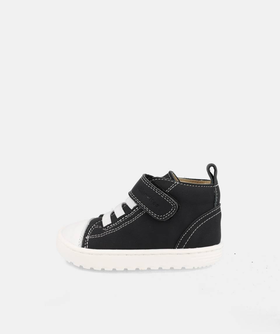 chaussure montante noire avec velcro, lacets élastiques blancs et semelle blanche