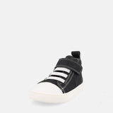 chaussure montante noire avec velcro, lacets élastiques blancs et semelle blanche