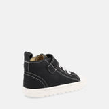 chaussure montante noire avec velcro, lacets élastiques blancs et semelle blanche