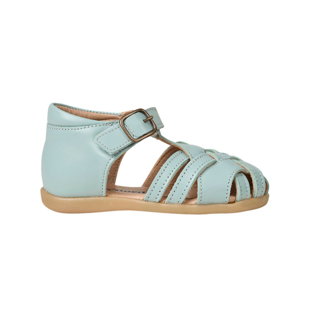 Sandale flexible pour bébé dans une belle couleur bleu pastel, avec velcro sous une boucle décorative.