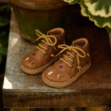 Une paire de chaussures pour enfant à lacets couleur latté avec broderie de chiens.