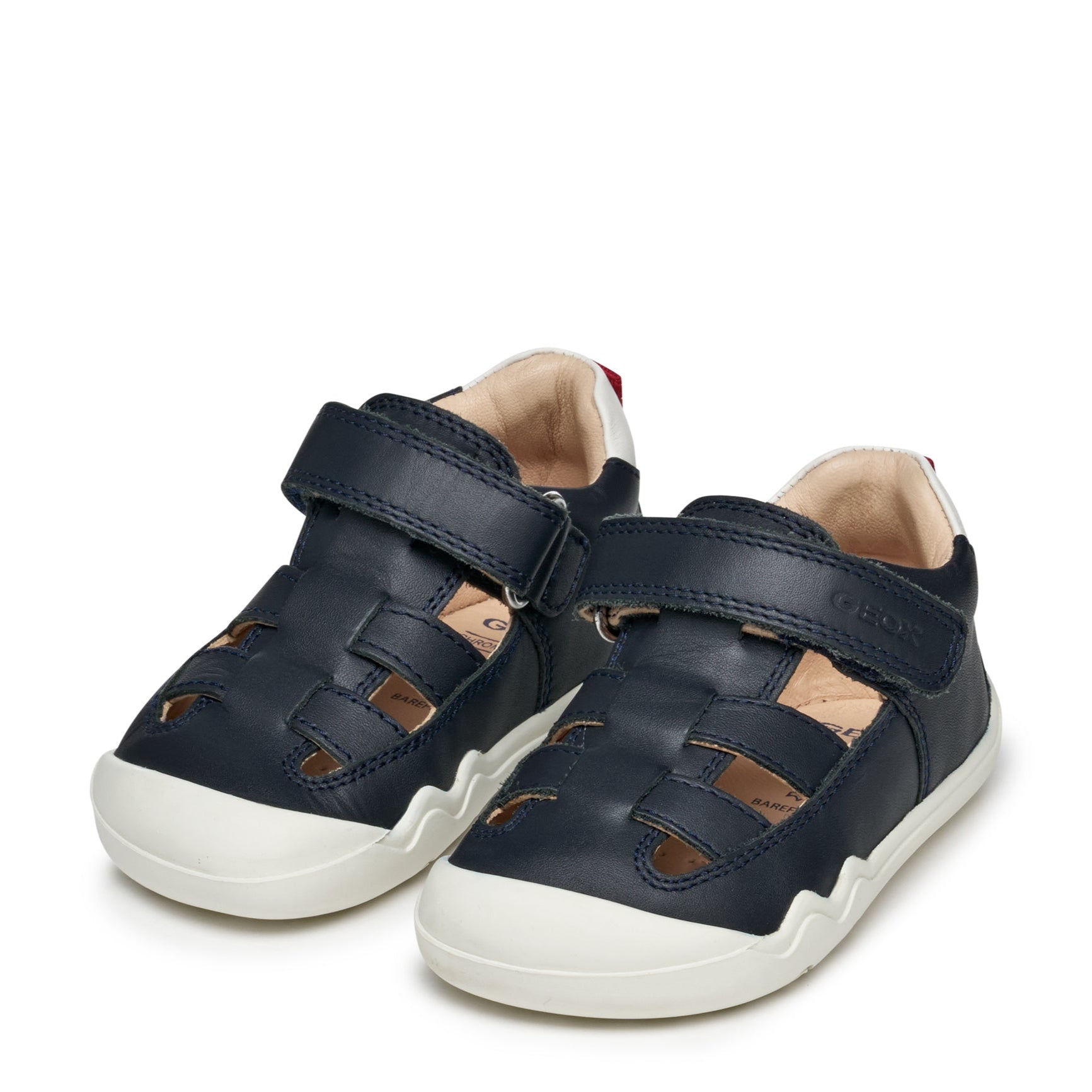 Une paire de sandales pour bébé, couleur marine, avec le bout blanc et fermé avec attache velcro.
