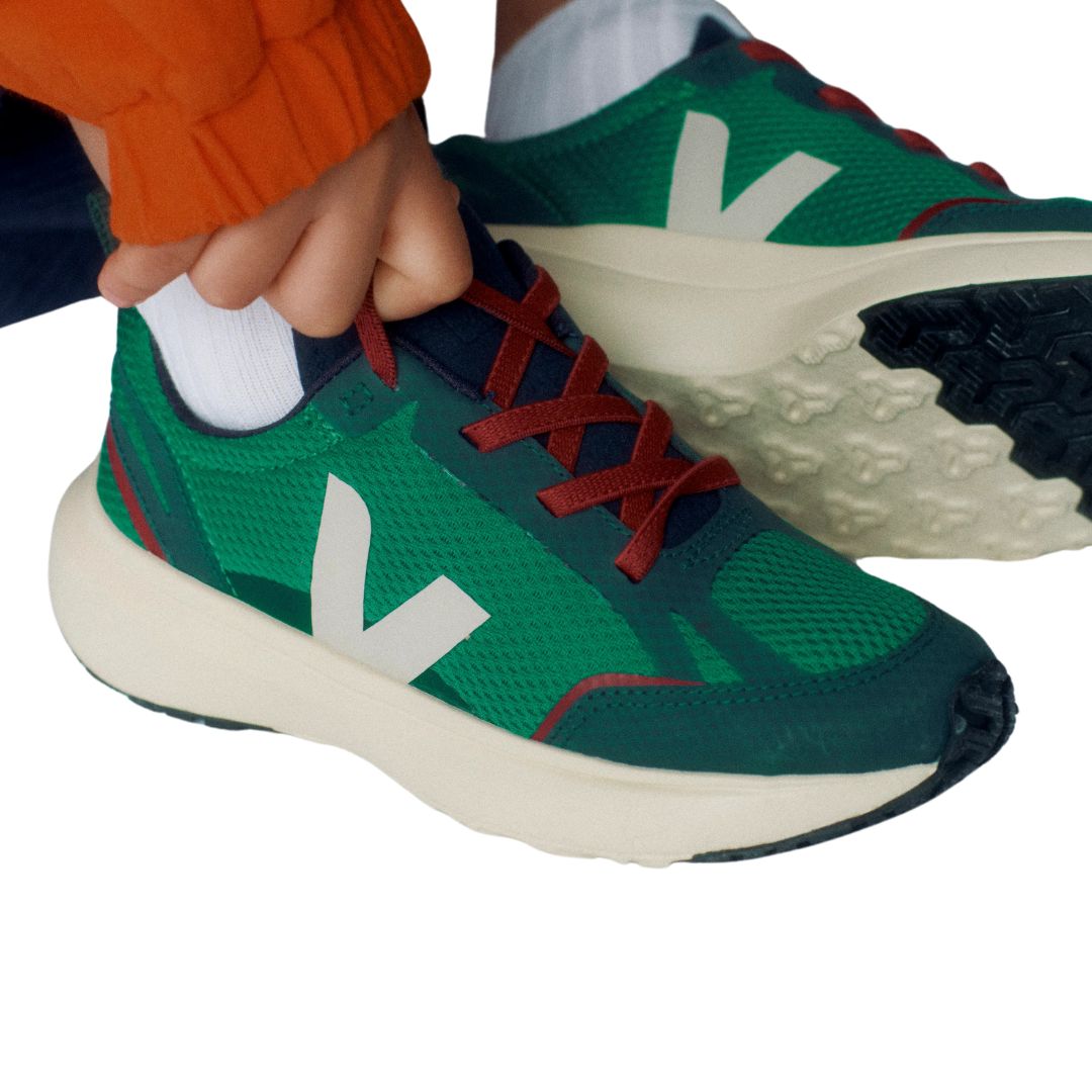 Un enfant porte des chaussures sport VEJA canary vert avec V blanc.
