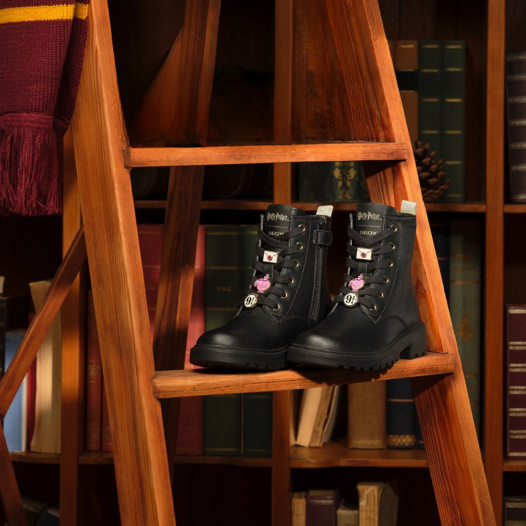Bottines noires mi-saison pour vos filles sur un escalier en bois. Pour les minis-fashonistas fans de Harry Potter. Avec des pins qui rappellent cet univers magique!