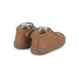 Chaussure premiers-pas pour bébé Pom d'Api en cuir nappa brun, avec des lacets élastiques.