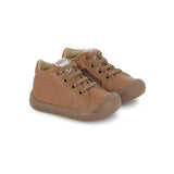 Chaussure premiers-pas pour bébé Pom d'Api en cuir nappa brun, avec des lacets élastiques.
