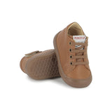 Chaussure premiers-pas pour bébé Pom d'Api en cuir nappa brun, avec des lacets élastiques.