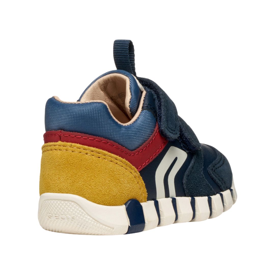 chaussure enfant en bi-matière bleu foncé, rouge et jaune, avec motifs rayures sur la semelle et fermeture à velcro.