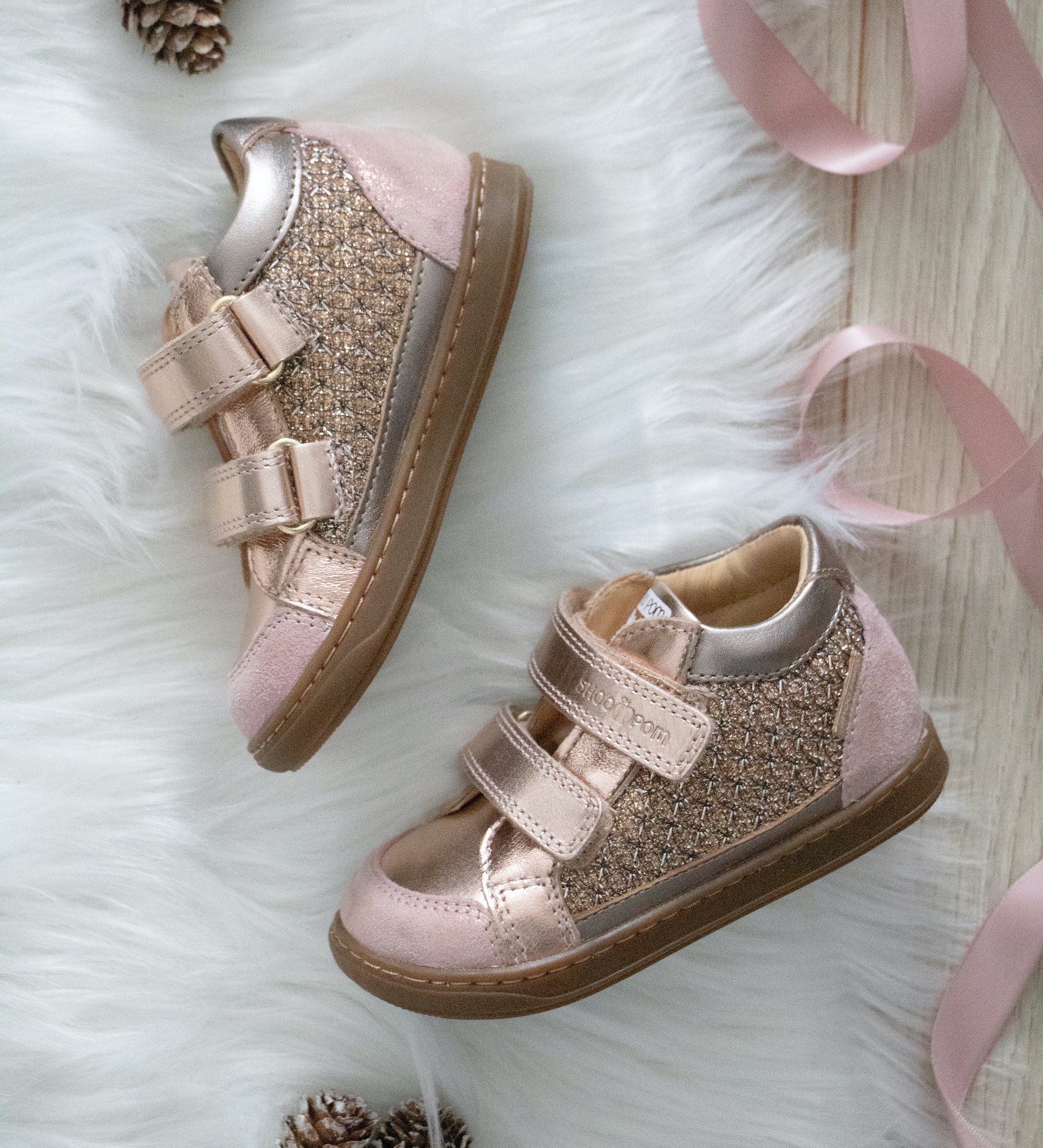 Chaussures premiers pas pour enfants rose à velcros sur un tapis blanc