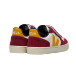 Chaussure enfant rouge bordeaux, blanche et jaune, avec trois velcros et semelle blanche.