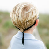 Enfant qui porte les lunettes Babiators avec la sangle noire attachée à la tête.