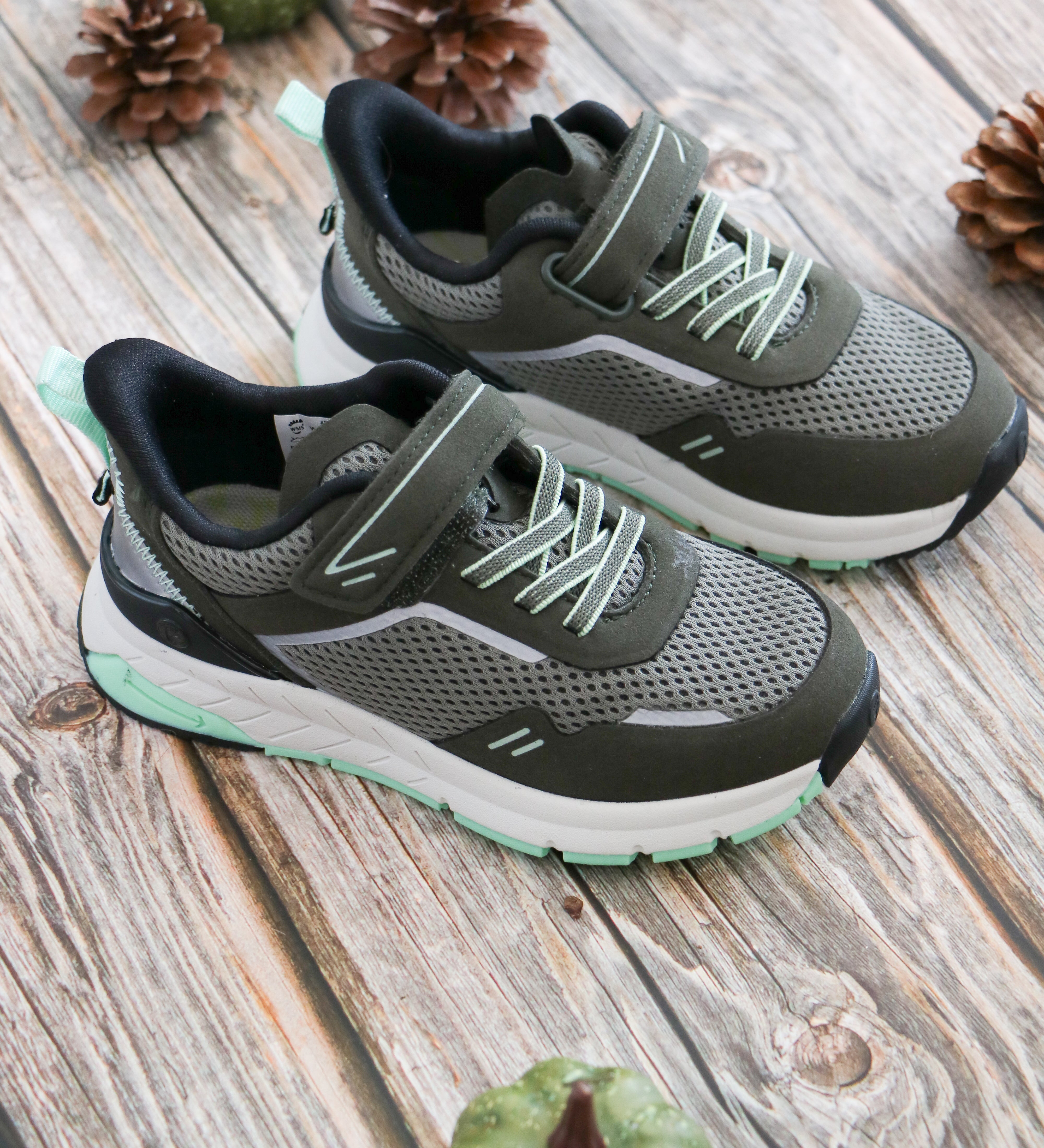 Espadrilles gris et vert avec velcro et lacet élastique sur planche de bois. 