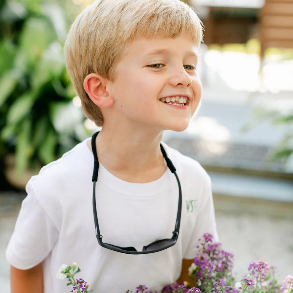 Enfant qui porte les lunettes Babiators avec la sangle noire attachée au cou.