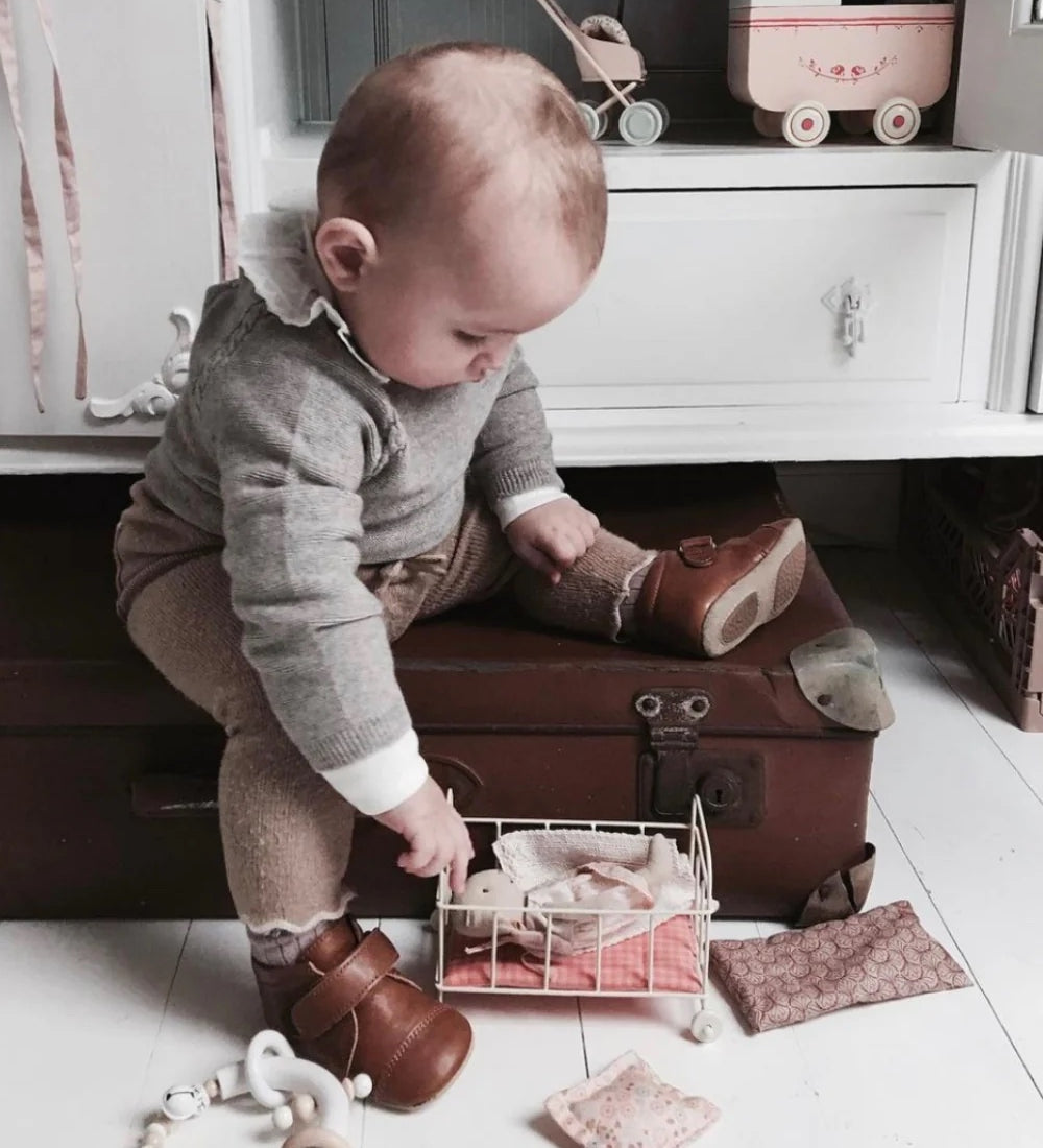 Un bébé avec des chaussons souples couleur cognac