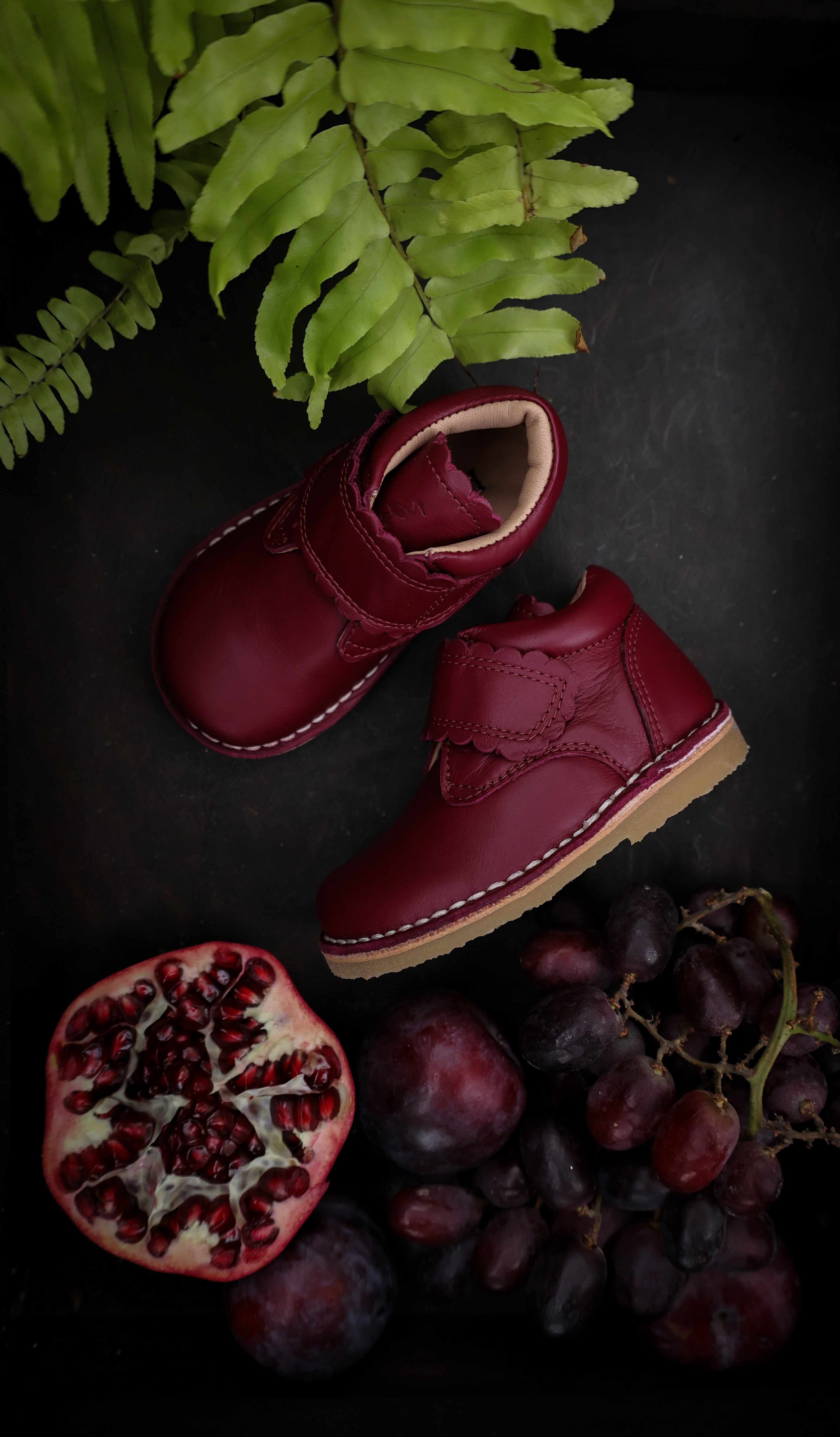 Chaussure Petit Nord pour enfant couleur Fuschia  avec velcro, à côté d'une Pomme grenade de la même couleur. 