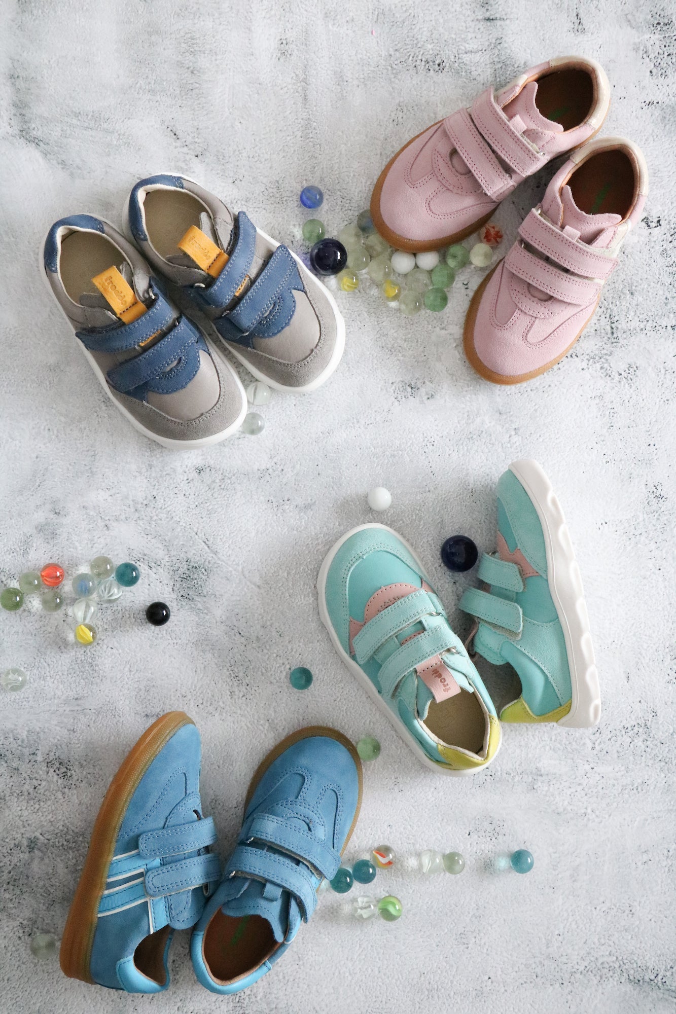 Des paires de seakers pour garçon et filles de différentes couleurs, avec des billes à jouer au sol. 